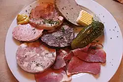 Brotzeitplatte, clockwise from the mustard: Brawn, liver sausage, butter, cucumber, smoked meat, white Pressack (head cheese), Göttinger and red Pressack in the middle.